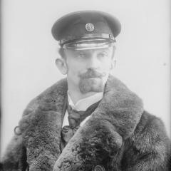 Photographie d'Emile Duchemin, photographe, habillé d'un manteau de fourrure et d'une casquette de chauffeur automobile