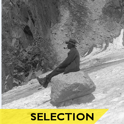Photo noir et blanc d'un homme dévalant une montagne sur un bloc de pierre