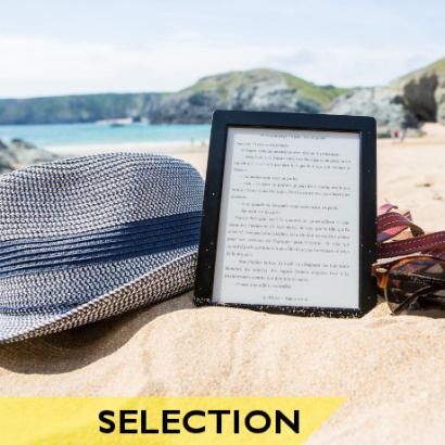 Chapeau, liseuse et lunettes de soleil sur le sable, face à la mer